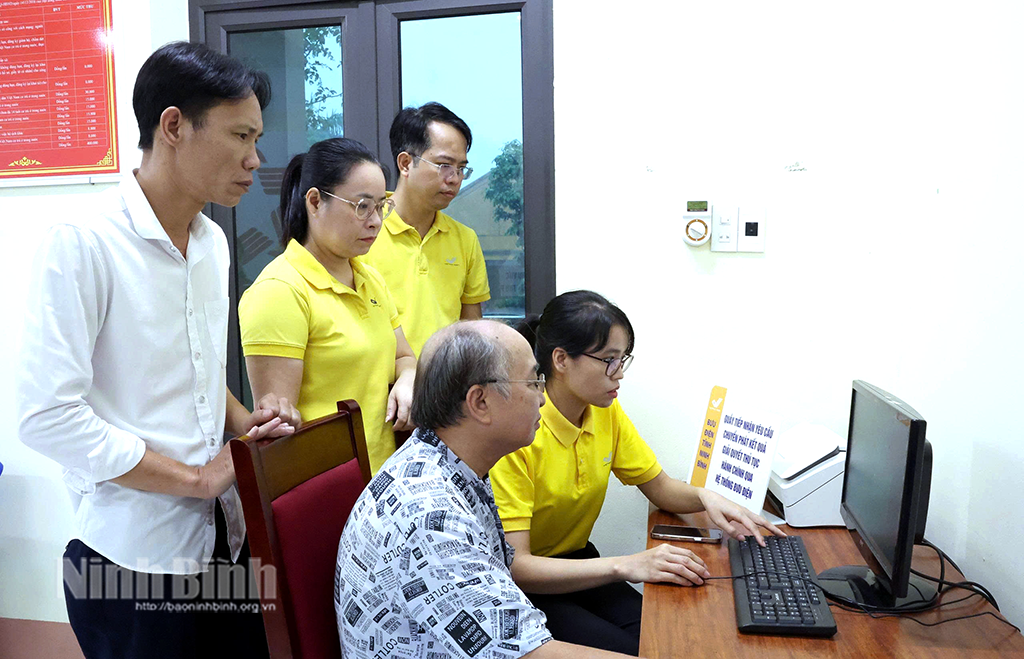 Cán bộ, nhân viên Bưu điện hướng dẫn người dân thực hiện TTHC trên môi trường điện tử. Ảnh: Minh Quang