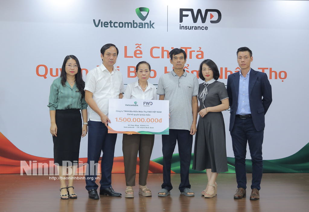 Lãnh đạo Ngân hàng Vietcombank chi nhánh NB trao bảng biểu trưng số tiền chi trả quyền lợi bảo hiểm cho khách hàng.