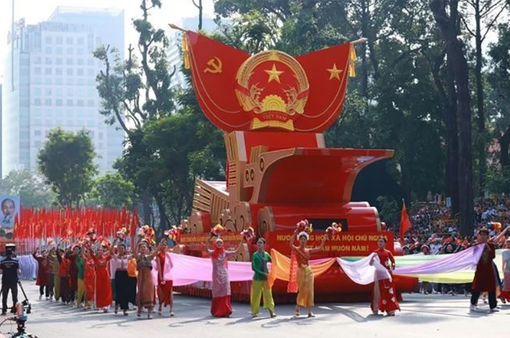 The vehicle carries the model of the National Emblem of the Socialist Republic of Vietnam in the parade. (Photo: VNA)
