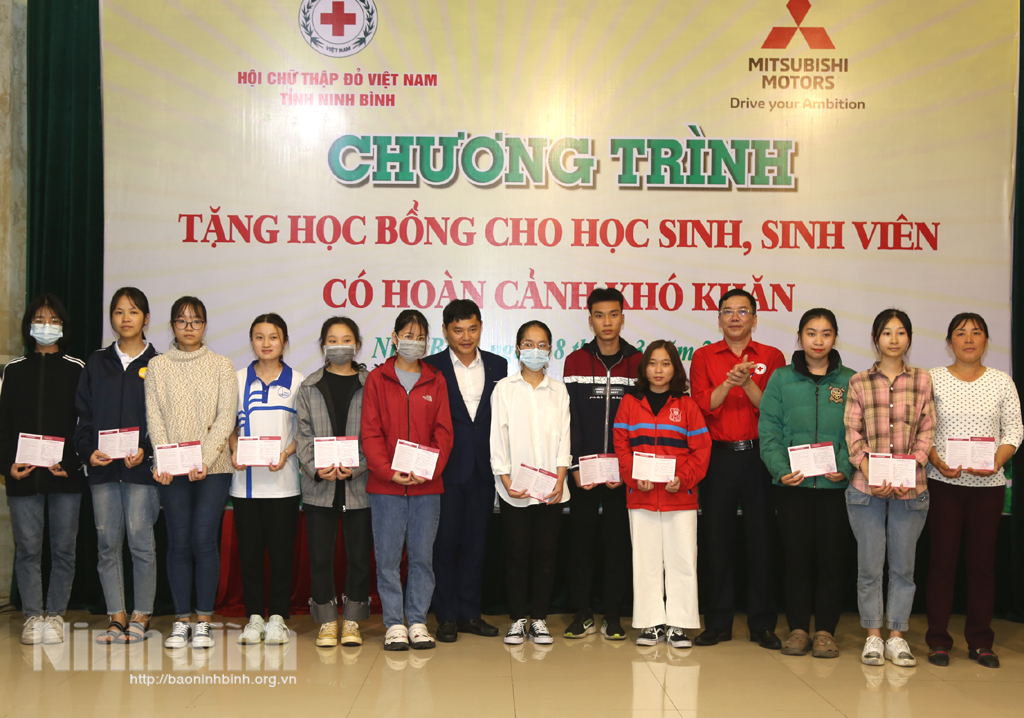 Representatives of The Red Cross Society of Ninh Binh province and the Mitsubishi Motors Vietnam Co. Ltd present scholarship to disadvantaged students.