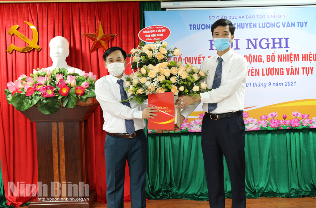 Head Department of Education and Training Phan Thanh Cong presents Decision and flower to the newly principal.