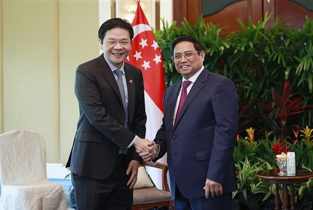 Prime Minister Pham Minh Chinh (R) shakes hands with Singaporean Deputy Prime Minister Lawrence (Photo: VNA)
