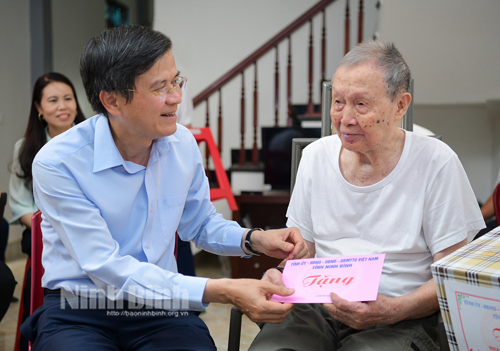 The Ninh Binh party chief presents gift to revolutionary contributor Dinh Ba Tai in Thong Nhat ward, Me town, Gia Vien district.